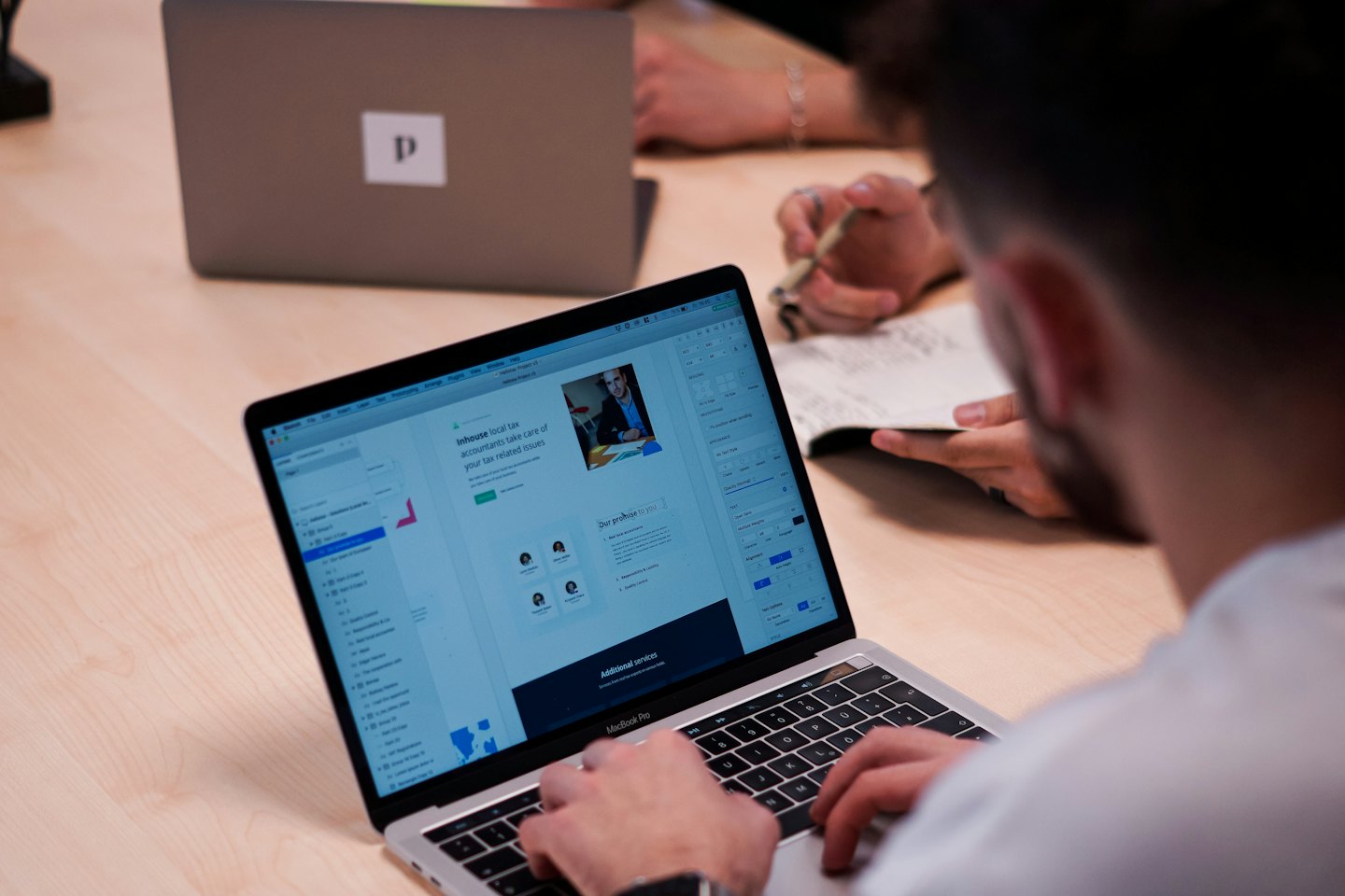 Dłonie piszące na laptopie z widokiem projektu strony internetowej.